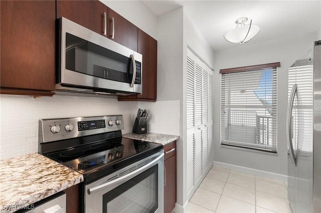 kitchen featuring dark brown cabinetry, light tile patterned floors, tasteful backsplash, baseboards, and stainless steel appliances