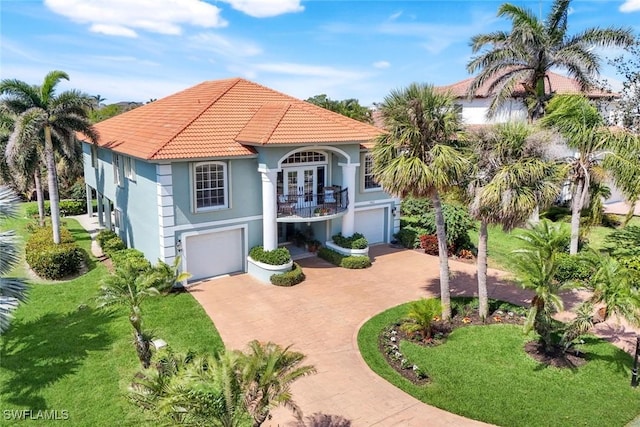 mediterranean / spanish-style house with driveway, a tile roof, an attached garage, french doors, and stucco siding