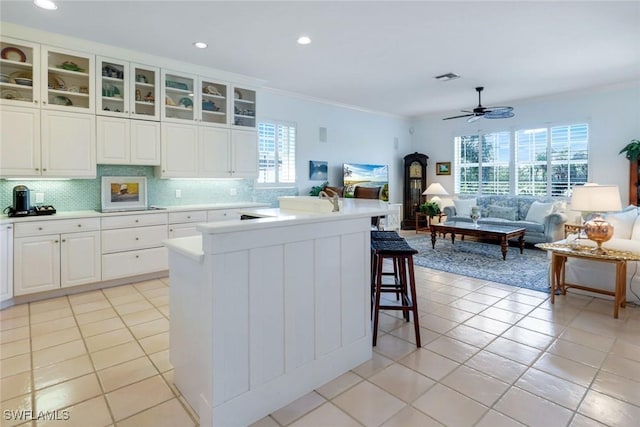 kitchen with a breakfast bar area, light tile patterned floors, visible vents, decorative backsplash, and ceiling fan