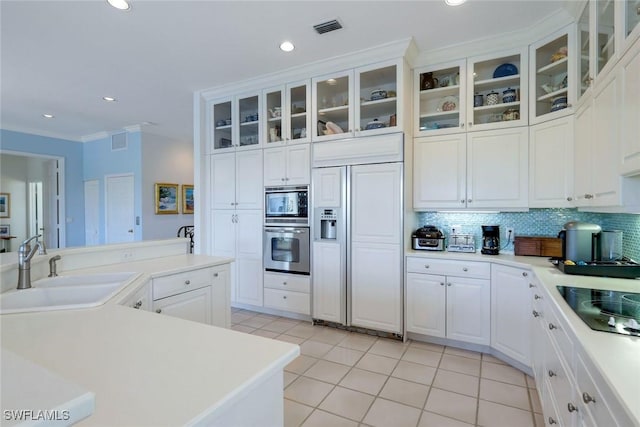 kitchen featuring light tile patterned floors, visible vents, decorative backsplash, built in appliances, and a sink