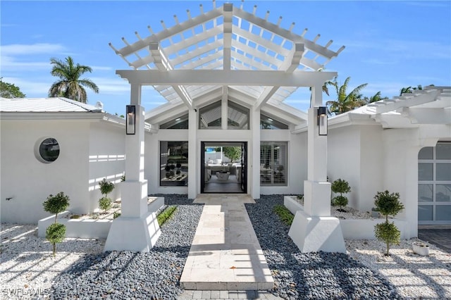 doorway to property featuring stucco siding and a pergola