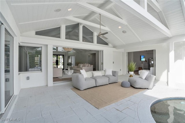 living area featuring high vaulted ceiling, beamed ceiling, a ceiling fan, and stone tile floors