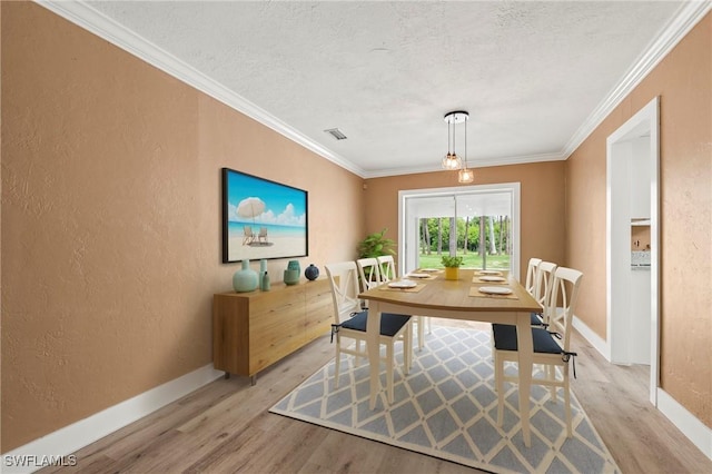 dining room with crown molding, light wood finished floors, a textured wall, a textured ceiling, and baseboards