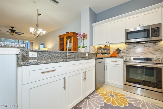 kitchen with decorative backsplash, appliances with stainless steel finishes, white cabinetry, a sink, and dark stone countertops