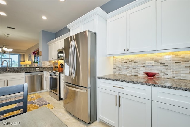 kitchen featuring stainless steel appliances, visible vents, decorative backsplash, white cabinets, and dark stone counters