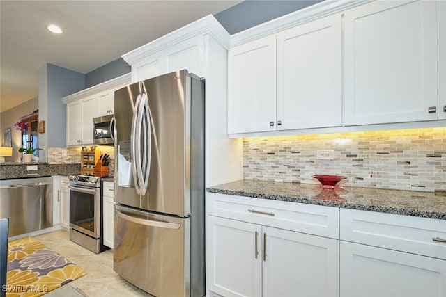 kitchen with recessed lighting, stainless steel appliances, white cabinets, backsplash, and dark stone counters