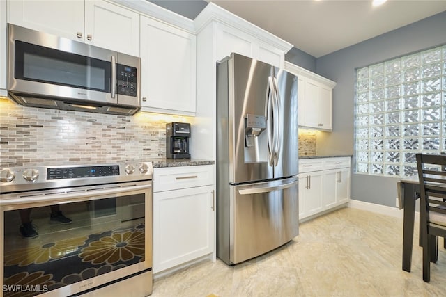 kitchen featuring dark stone counters, appliances with stainless steel finishes, decorative backsplash, and white cabinets