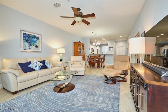 living area featuring ceiling fan with notable chandelier, light tile patterned flooring, and visible vents