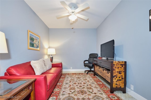 living area with a ceiling fan and baseboards