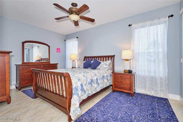 tiled bedroom featuring a ceiling fan, multiple windows, and baseboards