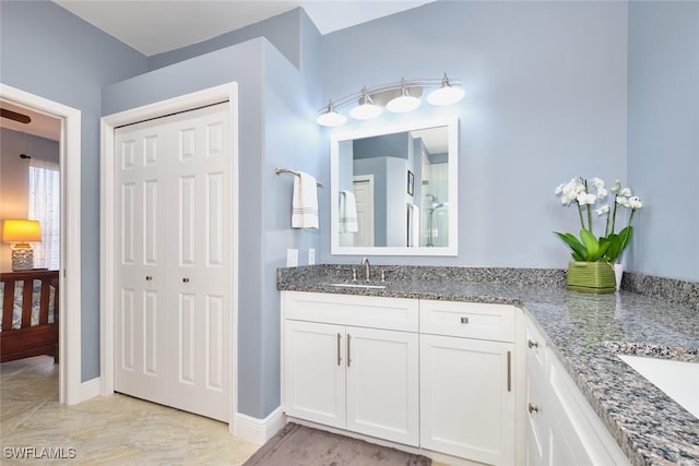 bathroom with double vanity, baseboards, and a sink