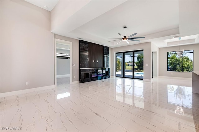 1316 SW 23rd St, Cape Coral, FL 33991 - unfurnished living room with a tray ceiling, baseboards, light marble finish floors, and ceiling fan