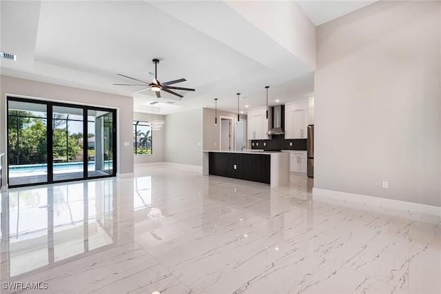 1316 SW 23rd St, Cape Coral, FL 33991 - unfurnished living room with baseboards, ceiling fan, light marble finish flooring, recessed lighting, and a tray ceiling