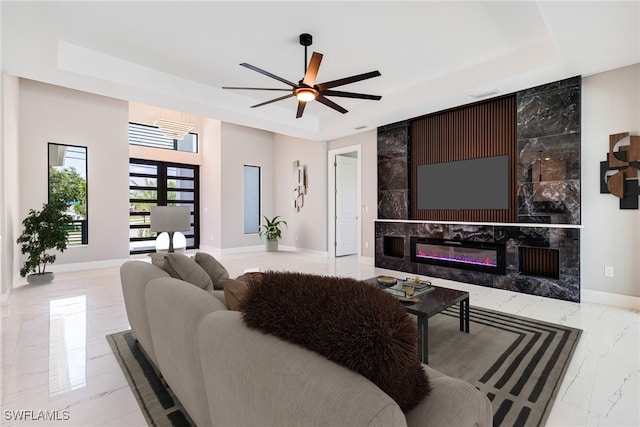 1316 SW 23rd St, Cape Coral, FL 33991 - living room featuring a raised ceiling, marble tiled floors, baseboards, a ceiling fan, and a fireplace