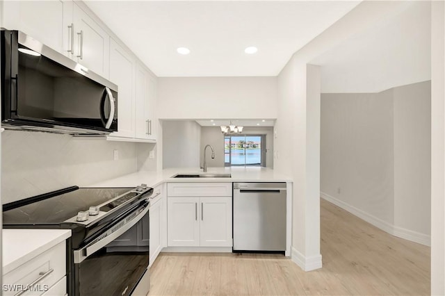 kitchen featuring stainless steel appliances, a sink, light countertops, and white cabinetry