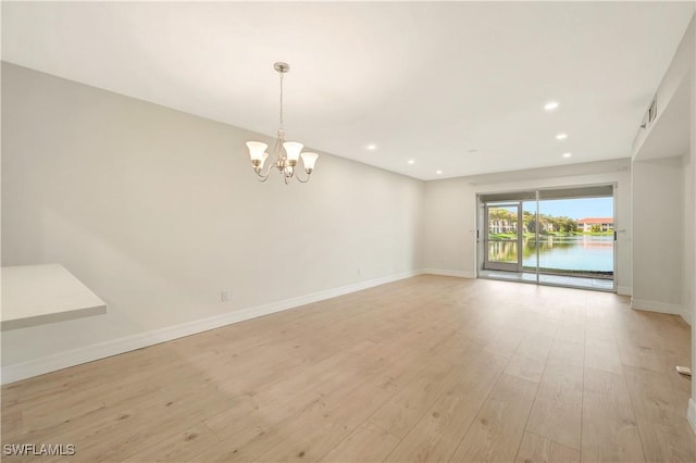 spare room with a chandelier, recessed lighting, light wood-style flooring, and baseboards