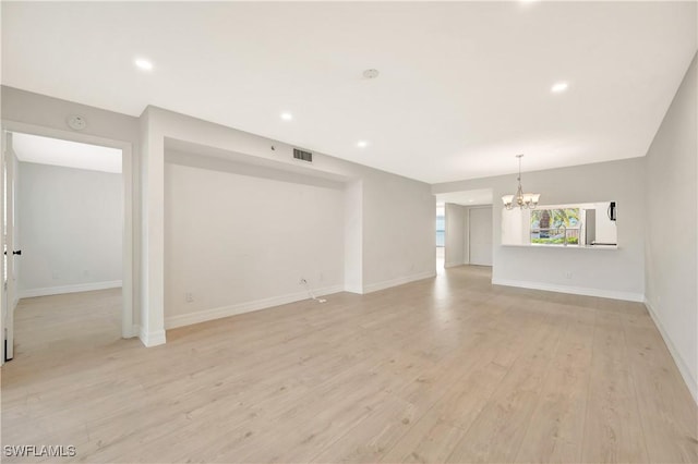 unfurnished living room with baseboards, visible vents, light wood finished floors, and an inviting chandelier