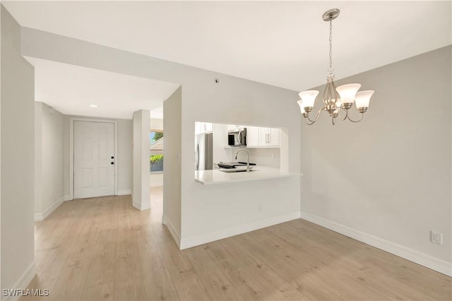 6448 Huntington Lakes Cir Unit 102, Naples, FL 34119 - kitchen featuring stainless steel appliances, a chandelier, light countertops, white cabinets, and light wood finished floors