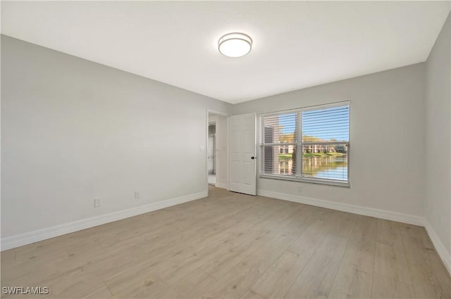 spare room with baseboards and light wood finished floors