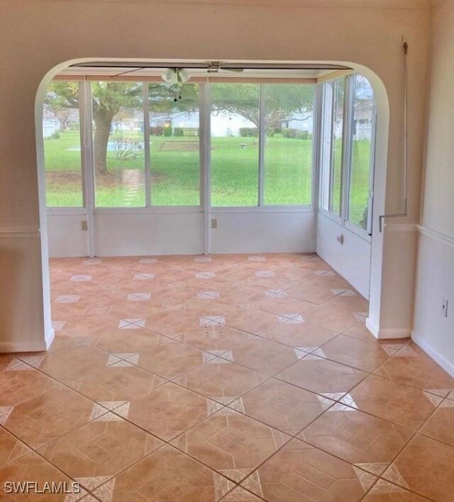 unfurnished room with light tile patterned floors and arched walkways