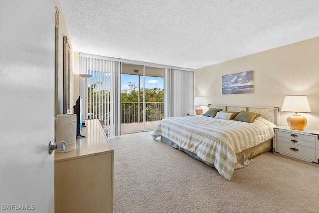 bedroom featuring light colored carpet, expansive windows, a textured ceiling, and access to outside