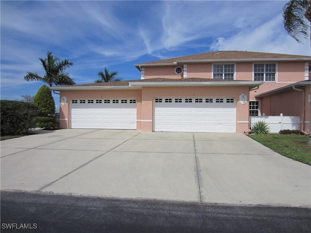 view of front of property featuring fence, concrete driveway, and stucco siding