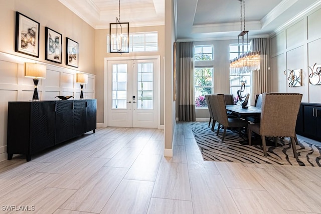 dining area with a tray ceiling, a decorative wall, a notable chandelier, and ornamental molding