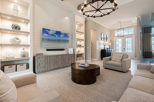 living area with baseboards, built in features, french doors, an inviting chandelier, and crown molding