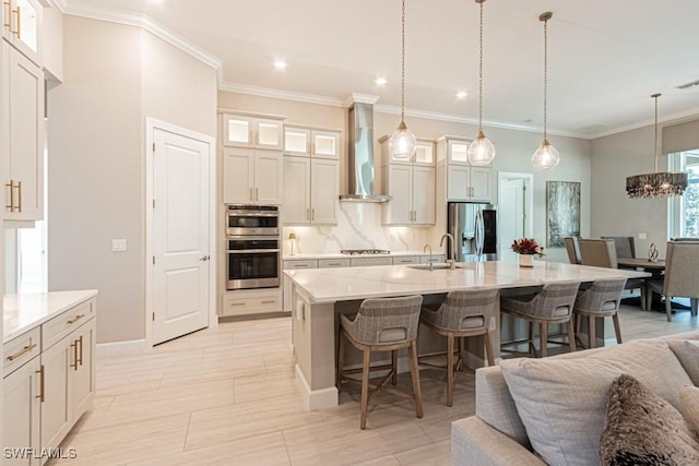 kitchen with appliances with stainless steel finishes, open floor plan, a sink, wall chimney range hood, and a kitchen bar