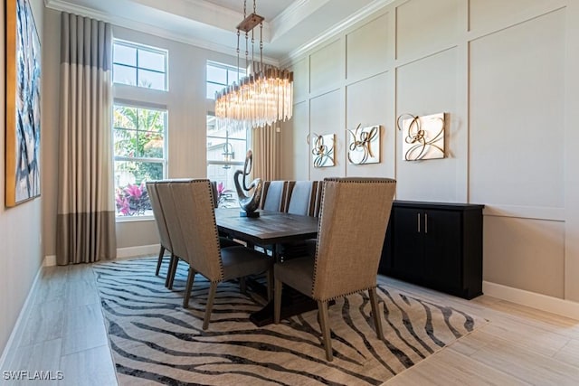 dining room featuring baseboards, an inviting chandelier, a tray ceiling, crown molding, and light wood-style floors