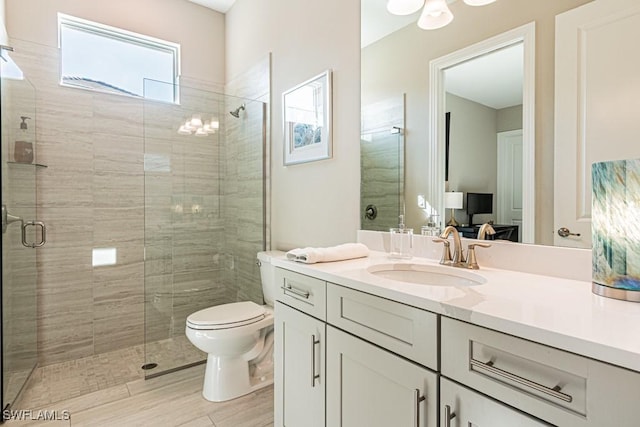 full bath with a stall shower, vanity, and toilet