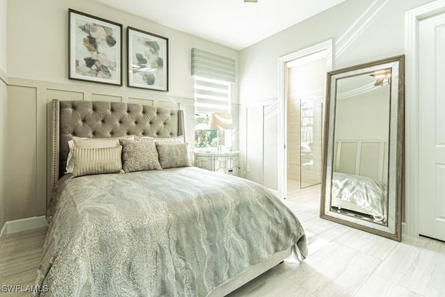 bedroom featuring a wainscoted wall and a decorative wall