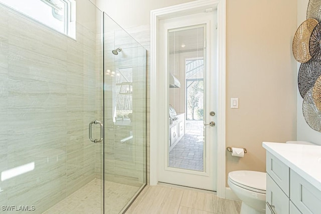 bathroom featuring toilet, a shower stall, and vanity