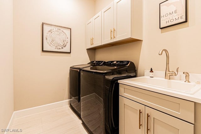 clothes washing area featuring light tile patterned floors, cabinet space, a sink, washer and dryer, and baseboards