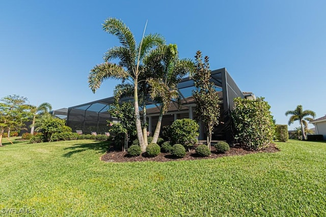 view of home's exterior featuring glass enclosure and a yard