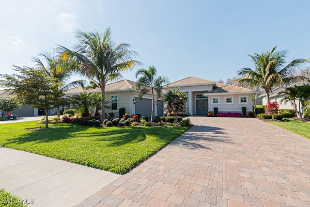 view of front of house featuring an attached garage, decorative driveway, and a front yard