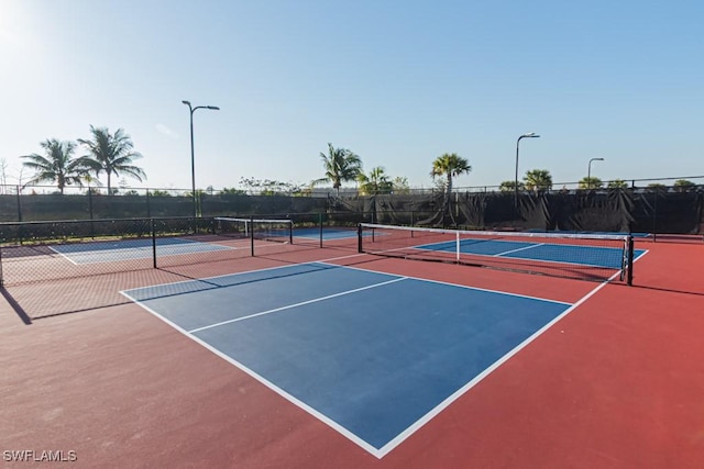 view of tennis court featuring community basketball court and fence