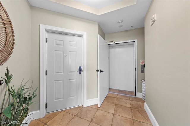 foyer entrance with light tile patterned floors and baseboards