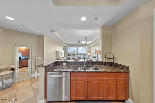 kitchen with visible vents, brown cabinetry, dark stone counters, stainless steel dishwasher, and a sink