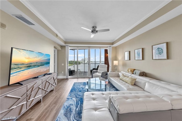 living room with a ceiling fan, wood finished floors, visible vents, and crown molding