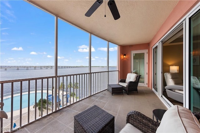 unfurnished sunroom featuring a water view and a ceiling fan