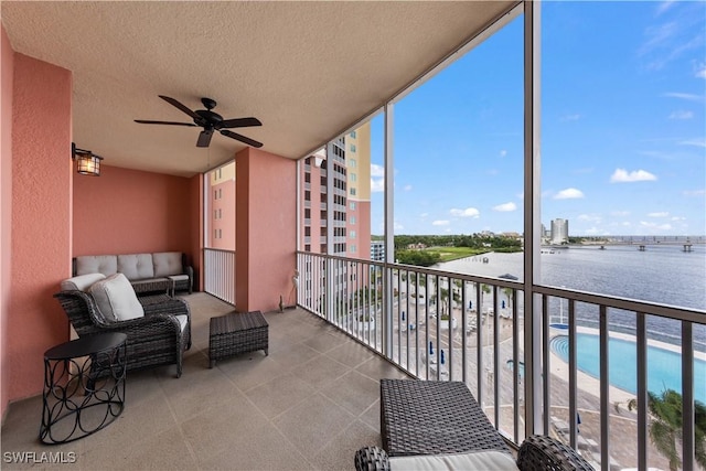 balcony with ceiling fan and a water view