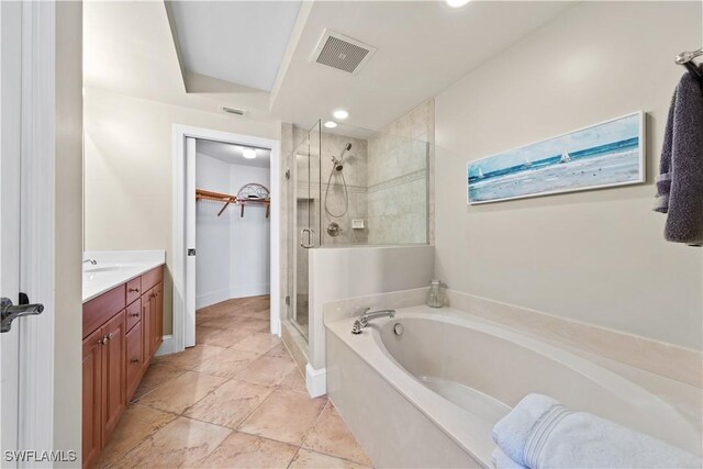 bathroom with a walk in closet, a garden tub, visible vents, a shower stall, and vanity