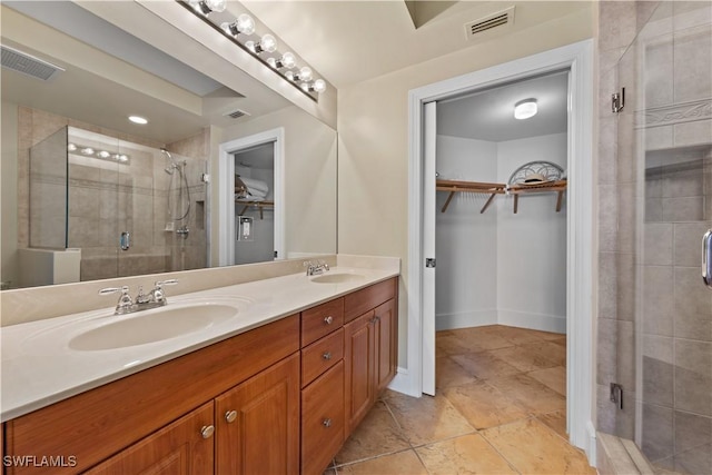 bathroom with visible vents, a sink, a shower stall, and a spacious closet