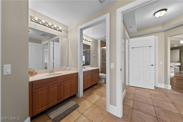 bathroom featuring a stall shower, baseboards, tile patterned floors, a sink, and two vanities