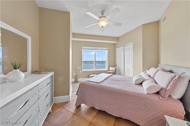 bedroom featuring light tile patterned floors, ceiling fan, visible vents, baseboards, and a closet