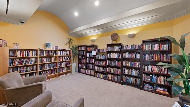 living area with lofted ceiling, carpet flooring, and wall of books