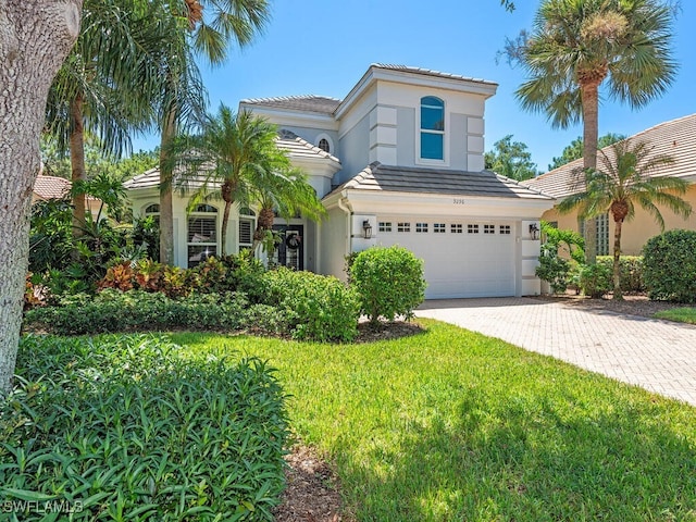 mediterranean / spanish-style home featuring a front lawn, decorative driveway, an attached garage, and stucco siding