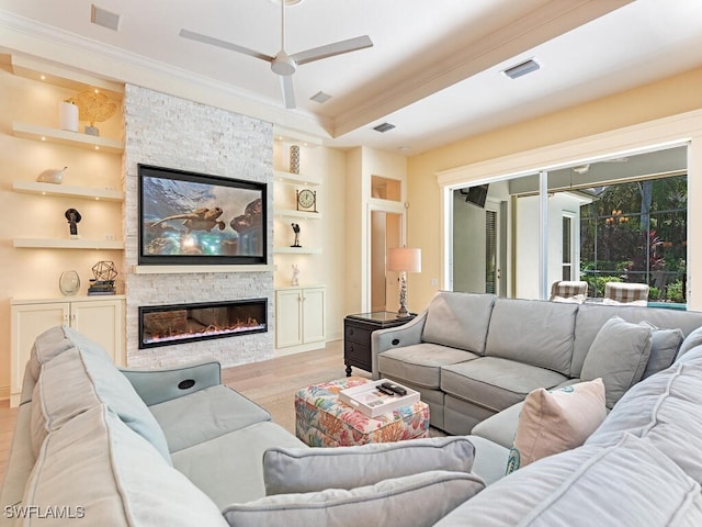 living area featuring visible vents, wood finished floors, crown molding, built in shelves, and a fireplace