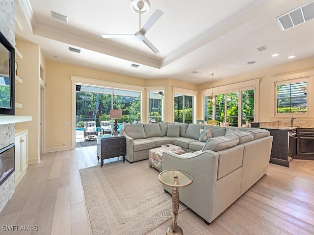 living room featuring crown molding, a tray ceiling, visible vents, and a ceiling fan